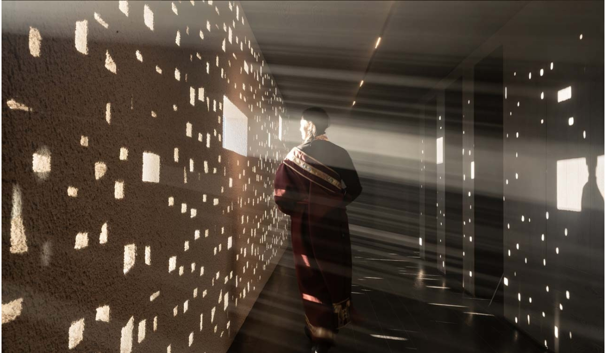 A figure in a flowing garment walks in a corridor illuminated by beams of light, casting patterned shadows on the walls.
