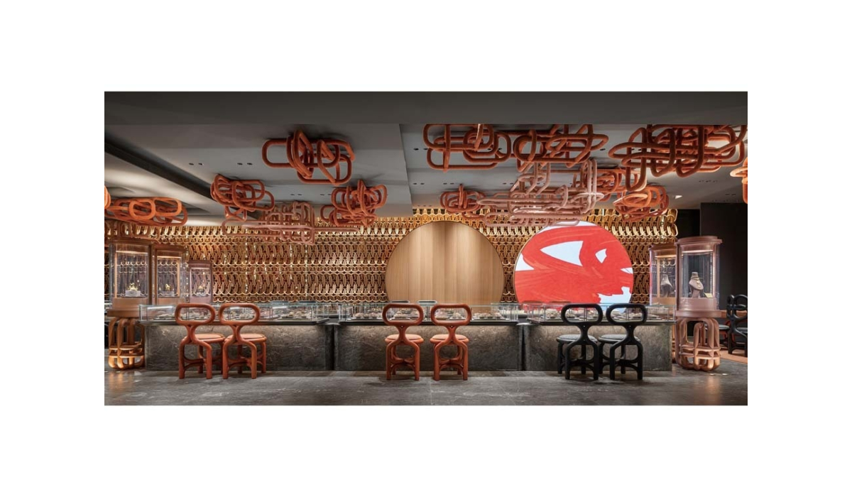 Luxury jewelry boutique with marble counters, interlocking wooden chairs and ceiling sculptures, arched wood backdrop and red disc artwork.