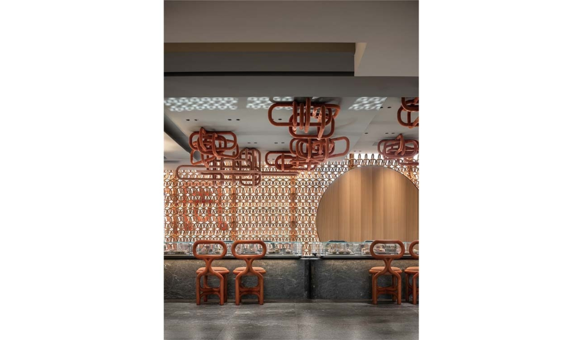 Dining counter with stone bar, orange loopback stools, orange ceiling loops and a lattice screen with a round wood panel and textured floor.