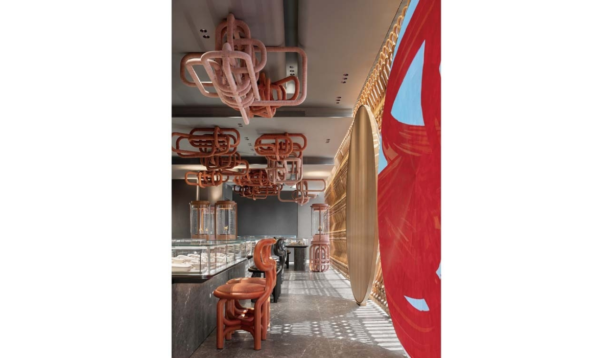 Modern boutique with coral tubular ceiling sculptures, glass display cases, looped coral stools, wooden lattice wall and red mural.