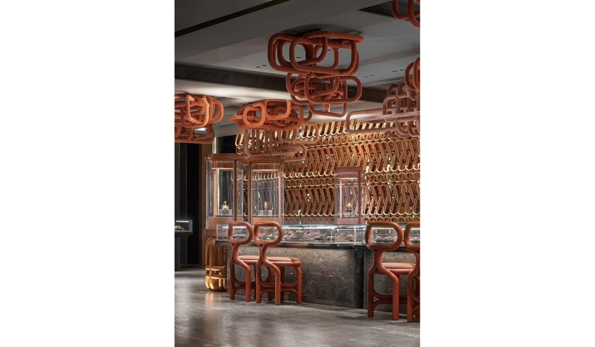 Luxurious jewelry interior with warm reddish wooden looped sculptures on ceiling and wall, glass display cases and matching looped stools.