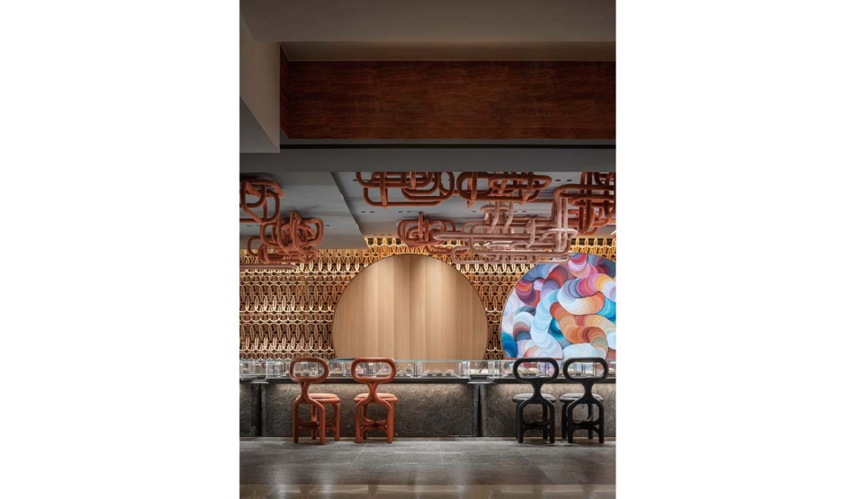 Modern bar with wooden lattice wall, round wood panel, colorful circular mural, looping wood ceiling fixtures and four sculptural stools.