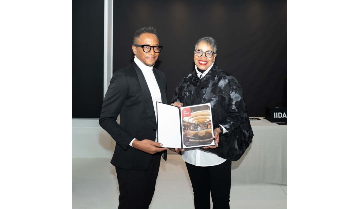 Two stylish individuals stand together, each holding a presentation folder. They are smiling, celebrating an achievement at a formal event.