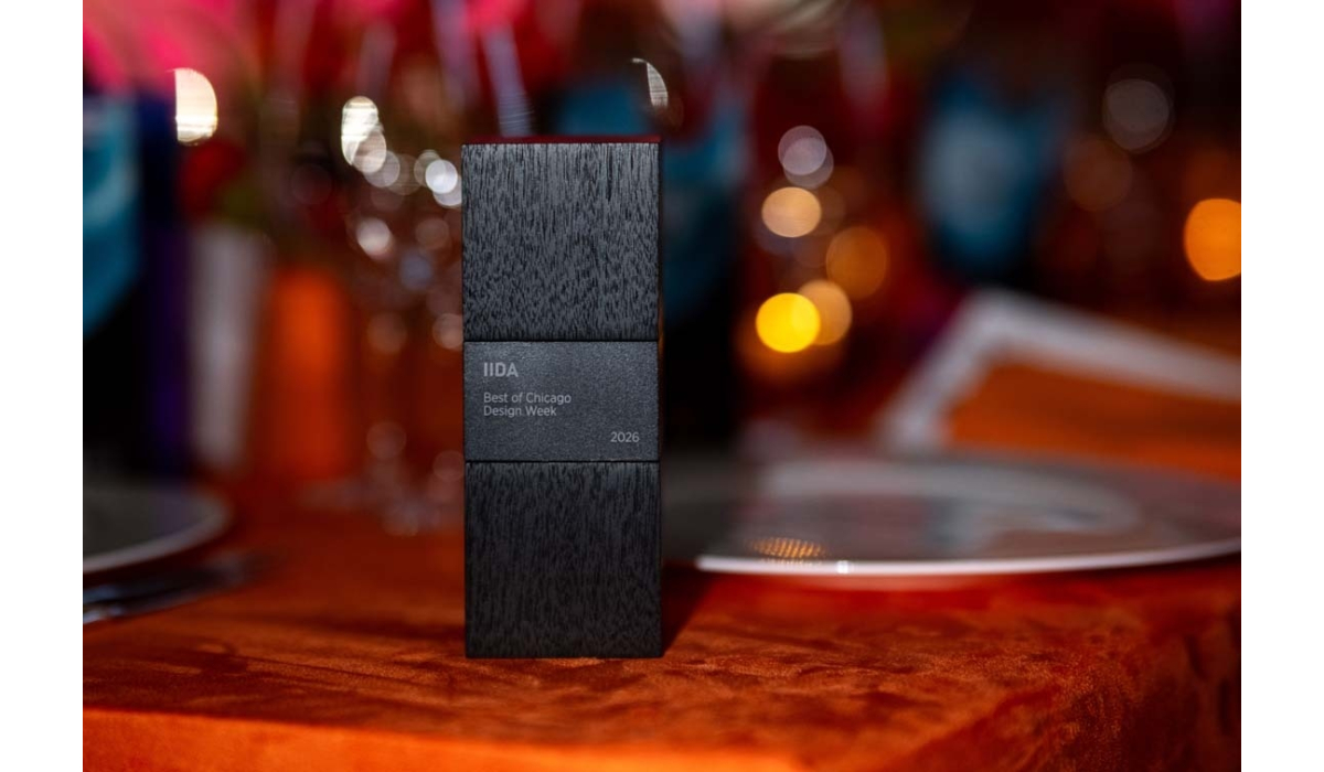 Tall matte black wood award engraved 'IIDA Best of Chicago Design Week 2026' standing on an orange velvet tablecloth with blurred bokeh.