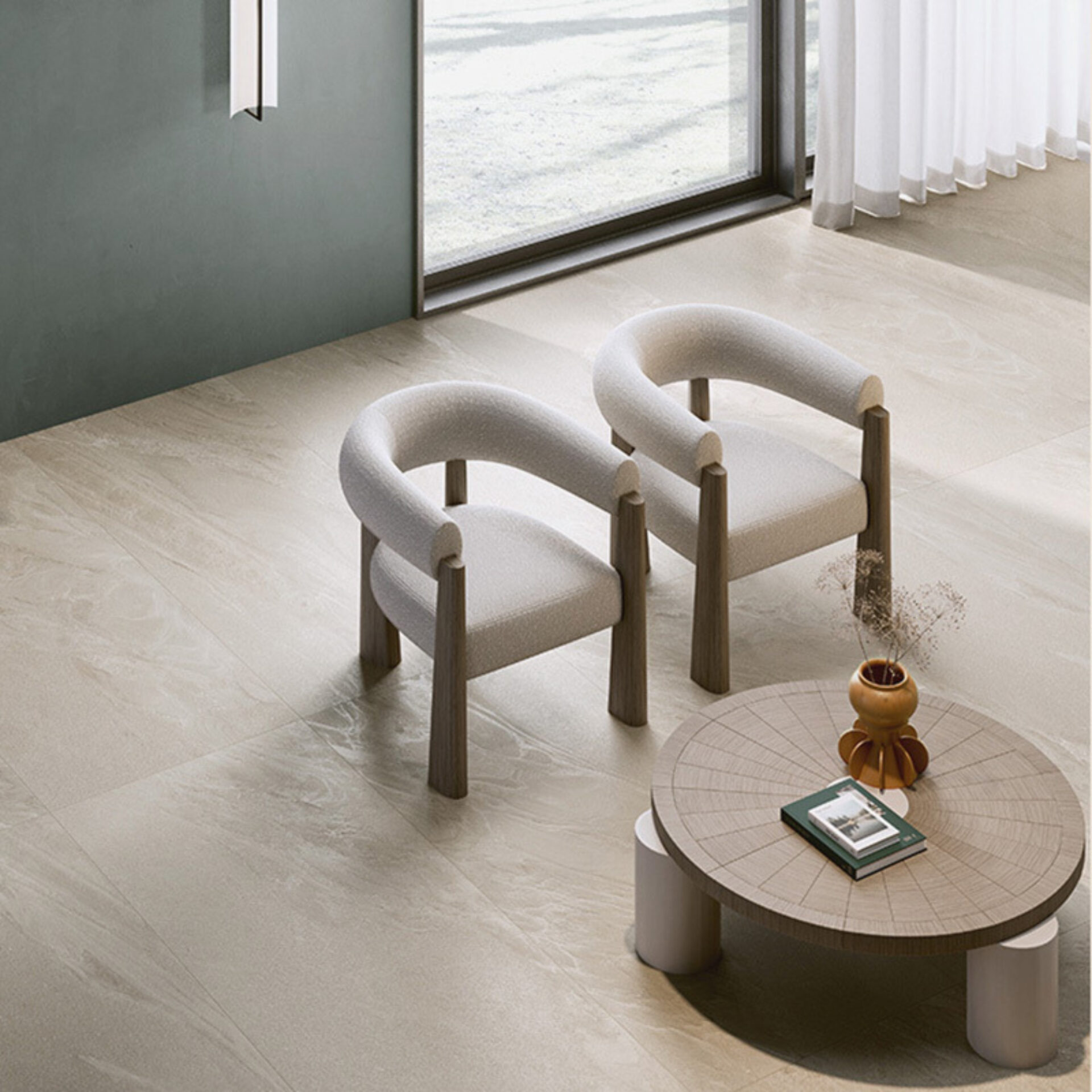 A modern interior scene featuring two cozy, rounded white chairs beside a circular wooden coffee table, with natural light filtering in.