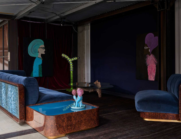 Luxurious dark lounge with blue velvet sectional and armchair, burl wood and turquoise panels, glass coffee table, whimsical portraits.