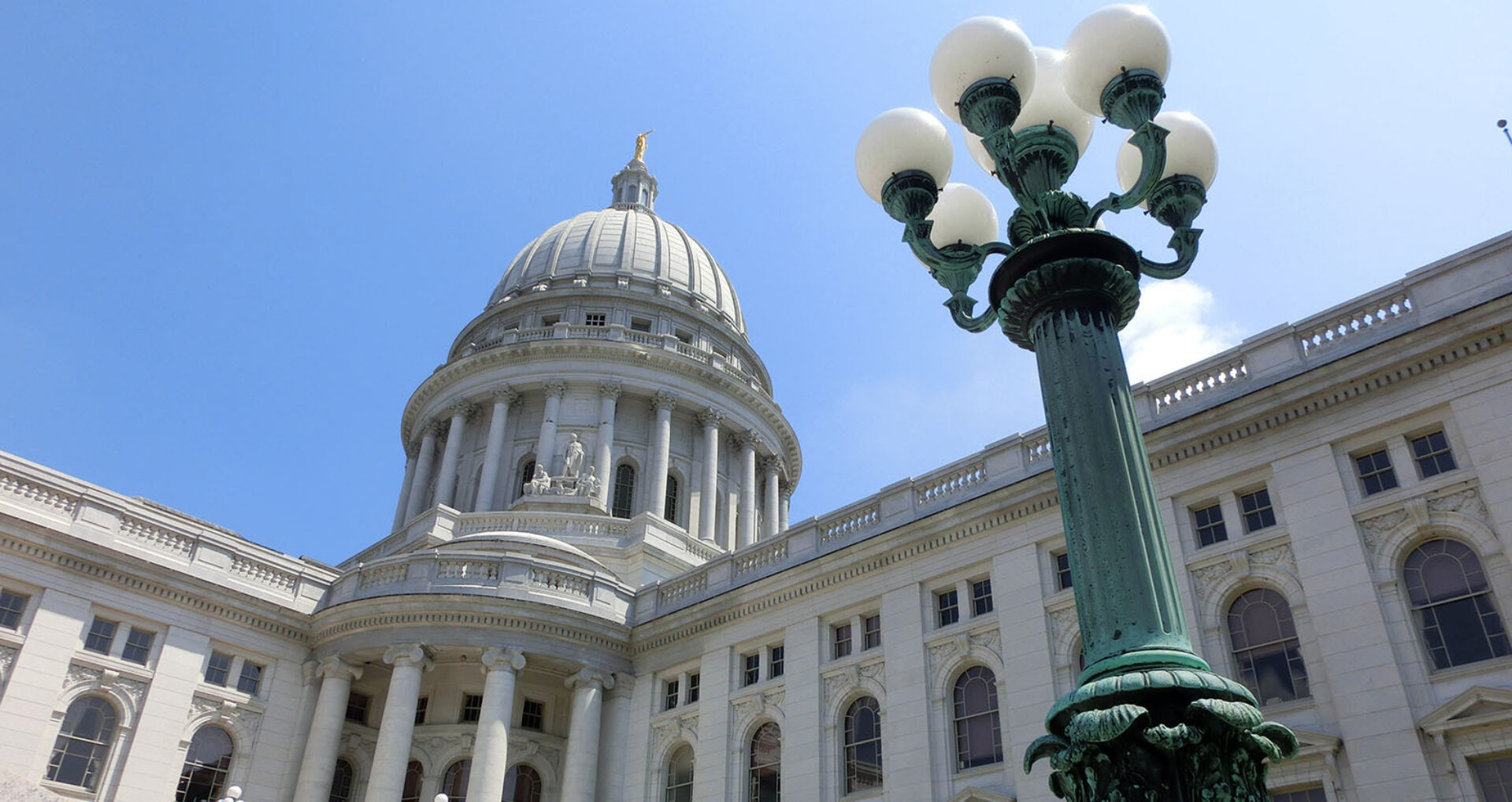 The ornate dome of a large government building towers above, accompanied by a vintage street lamp against a clear blue sky.