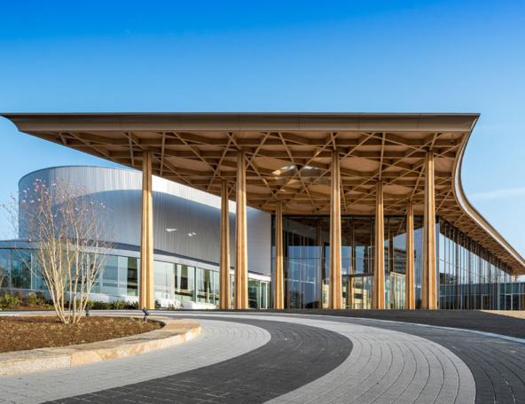 Modern architectural design showcases a striking building with a wooden overhang, large glass windows, and curving pathways.