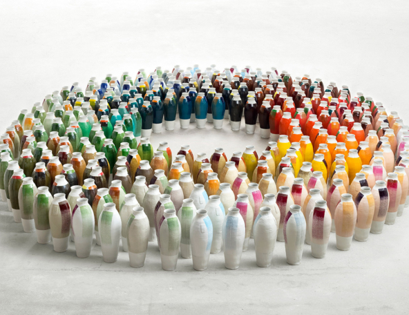 Hundreds of ceramic bottles arranged in a circular pattern, showcasing a vibrant array of colors across their surfaces.