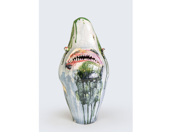 A ceramic vase featuring a shark's mouth, painted with vibrant colors and dripping designs, blending art and marine themes.