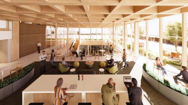 Sunlit wooden atrium coworking space with floor-to-ceiling windows, communal table, lounge pods, glass partitions and people working.