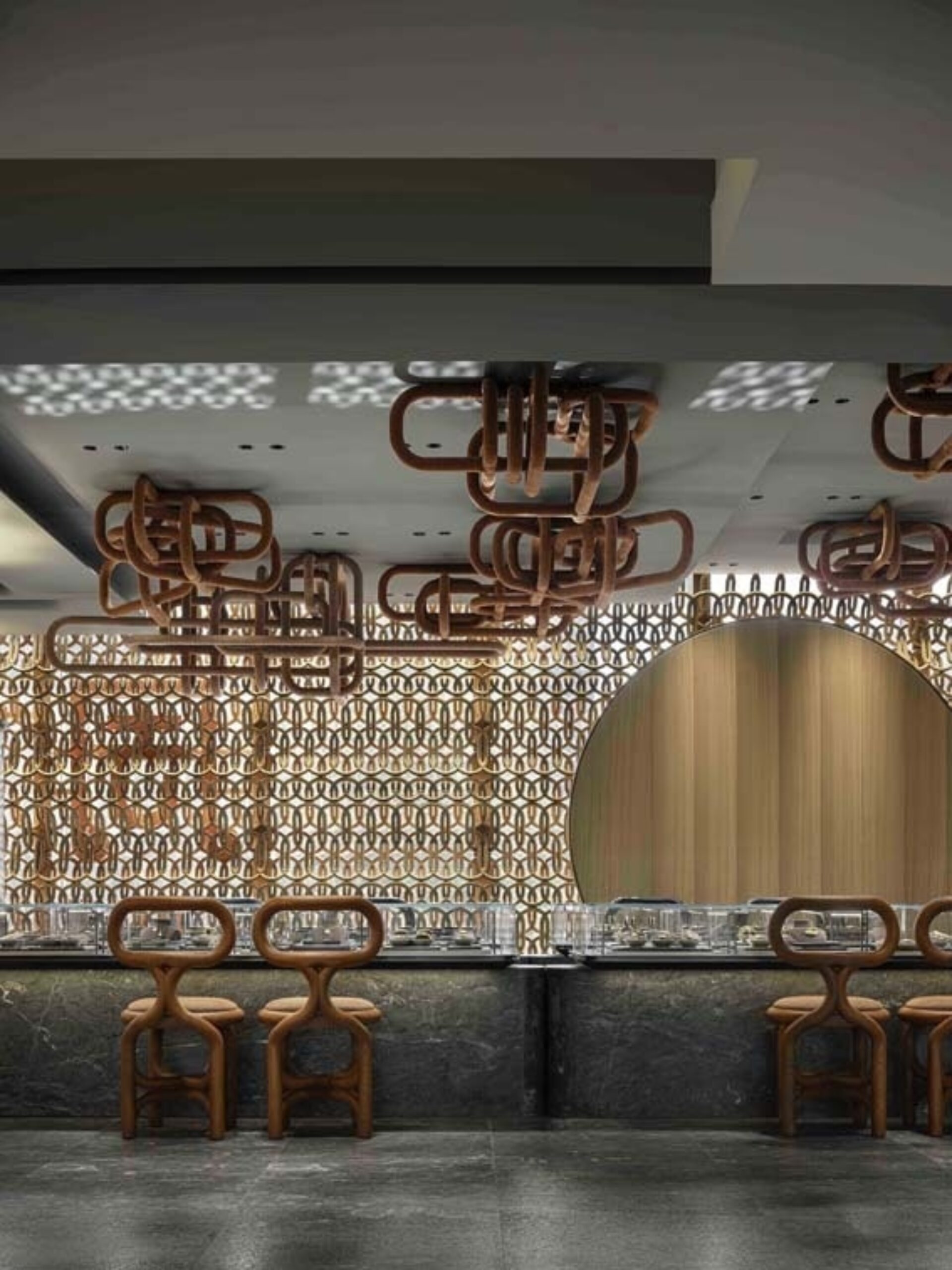 A modern restaurant interior featuring stylish red chairs, intricate wall patterns, and artistic light fixtures overhead.