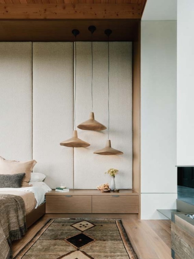 A cozy bedroom featuring a light color scheme, three pendant lights, and a textured wall, complemented by a stylish area rug.