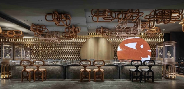 A modern interior featuring a sleek bar with artistic orange and black chairs, intricate decorative elements, and elegant display cases.