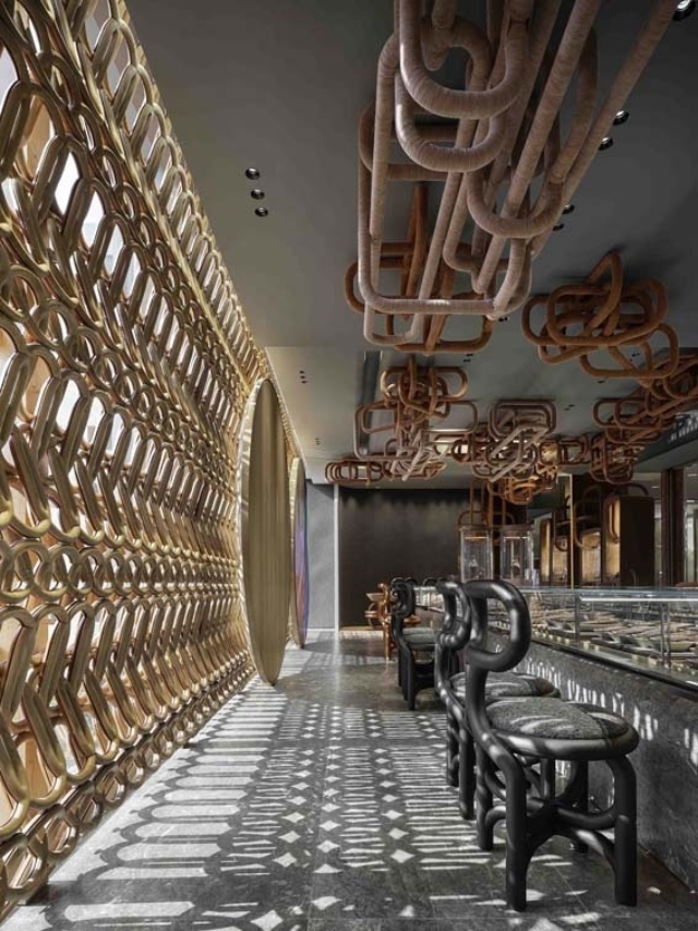 A modern interior featuring a unique wall design, sculptural overhead elements, and dark chairs against a sleek floor.