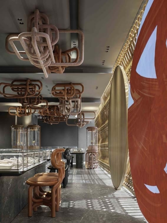 A modern interior featuring distinctive red and pink sculptural lighting, intricate wall designs, and stylish furniture in a jewelry store.