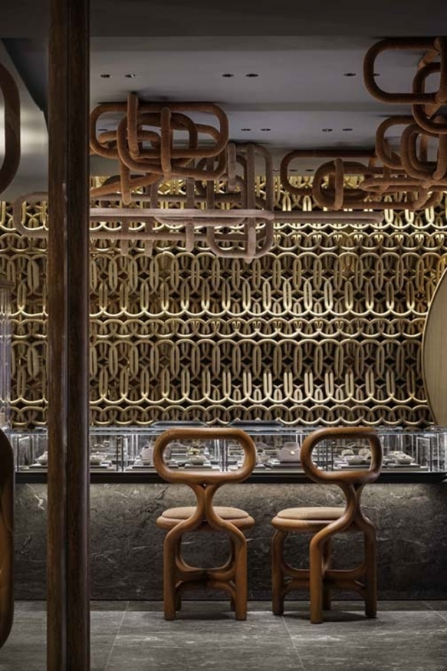 A modern interior features two stylish wooden chairs in front of a decorative wall with intricate patterns and hanging elements.