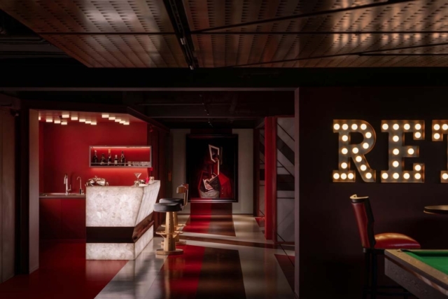 A stylish bar space features a marble counter, illuminated red accents, and a large artwork, creating a vibrant atmosphere for relaxation.