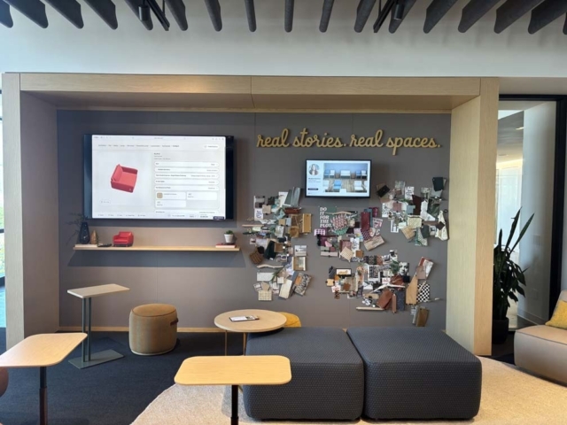 Showroom nook with two wall screens, a textured moodboard under the real stories. real spaces. sign, modular ottomans and low cafe tables.
