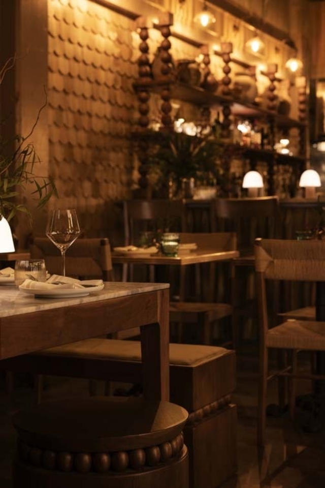 Elegant restaurant interior featuring wooden furniture, soft lighting, and decorative wall textures, creating a warm atmosphere.