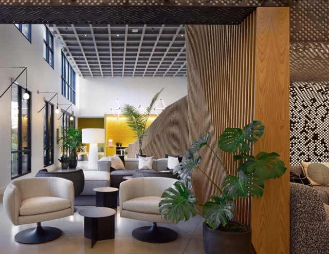 A modern lounge area features stylish furniture, including round chairs and a coffee table, with plants and textured wall designs.