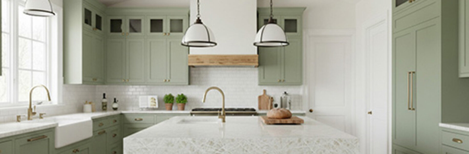 Bright farmhouse kitchen with sage green cabinets, white marble island, apron-front sink, brass faucets, pendant lights, potted herbs.